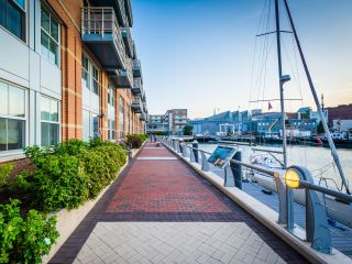 A Brick Walkway Next To A Building With Boats In The Water